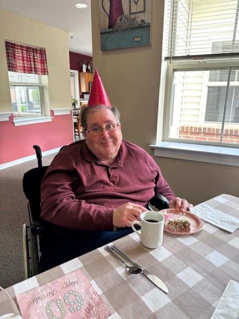 Resident celebrating with cake and a party hat