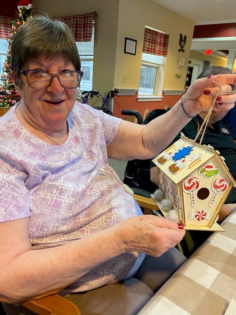 Resident proudly displaying a decorated gingerbread house.