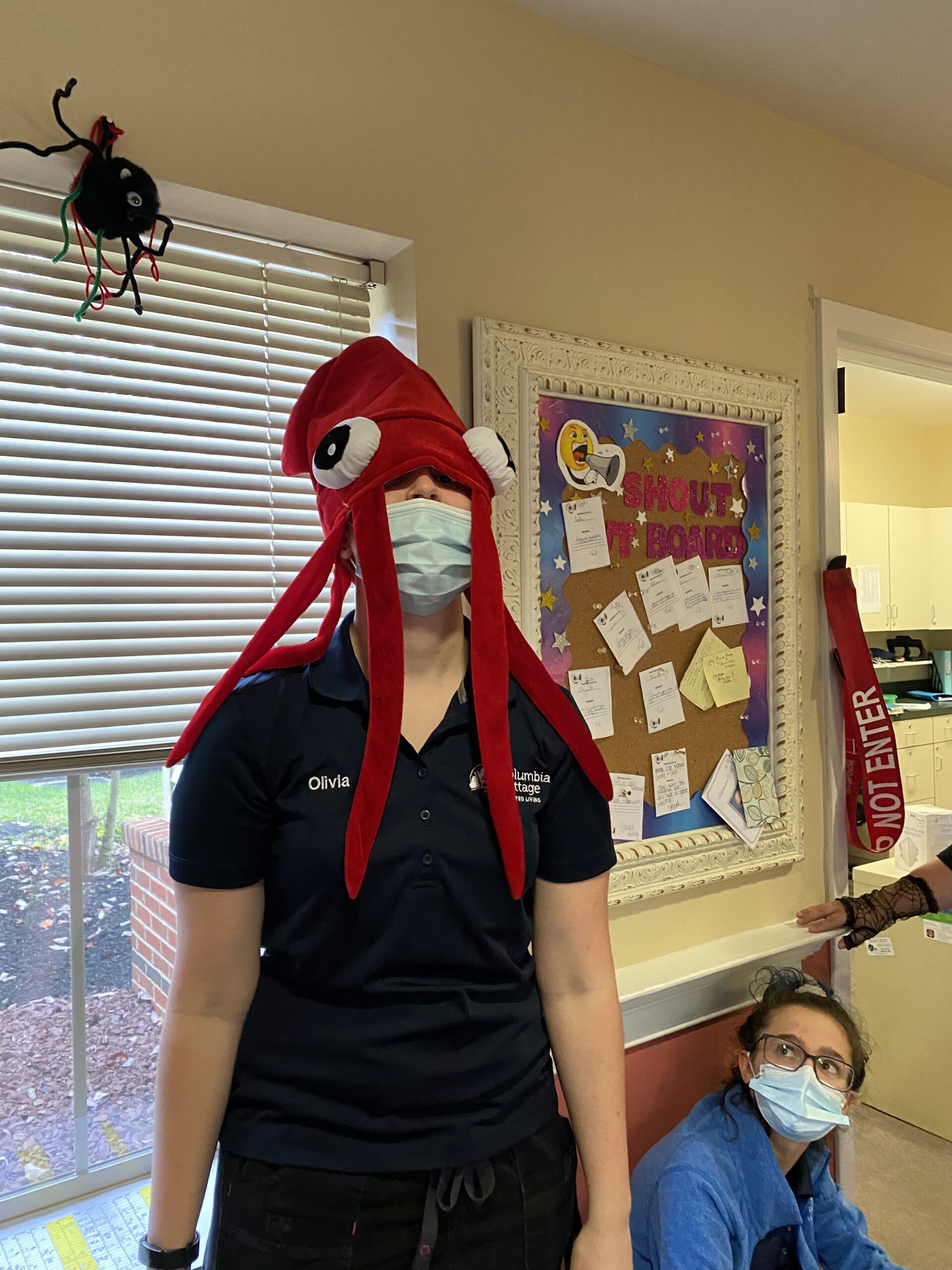 Staff member wearing a fun octopus hat in a common area.