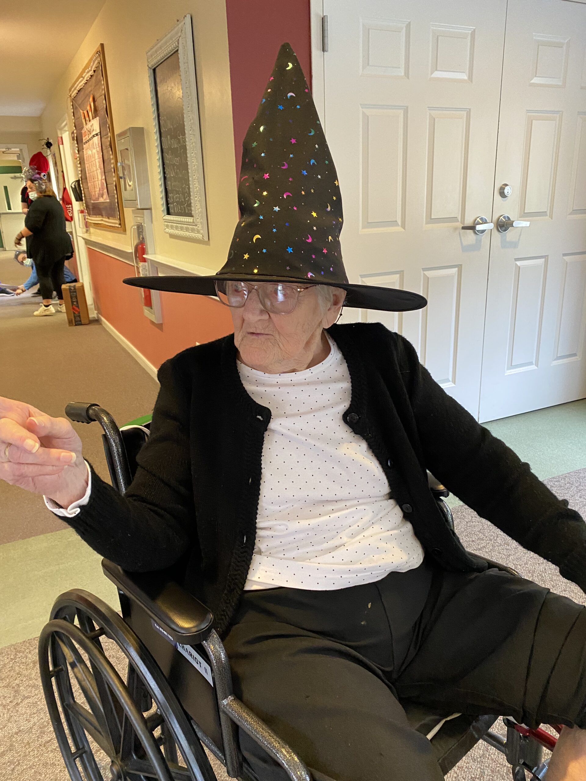 Resident in wheelchair wearing a festive hat.