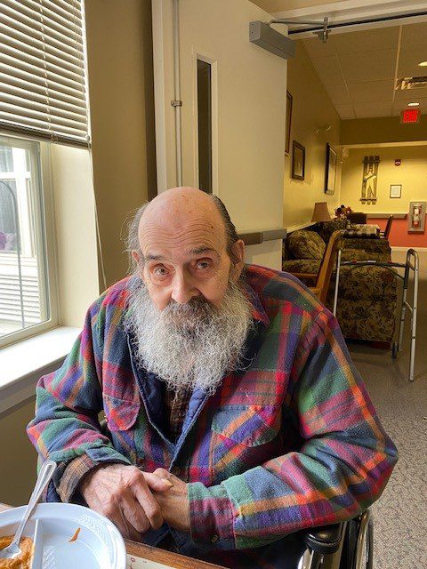 Resident with a beard in a plaid jacket indoors