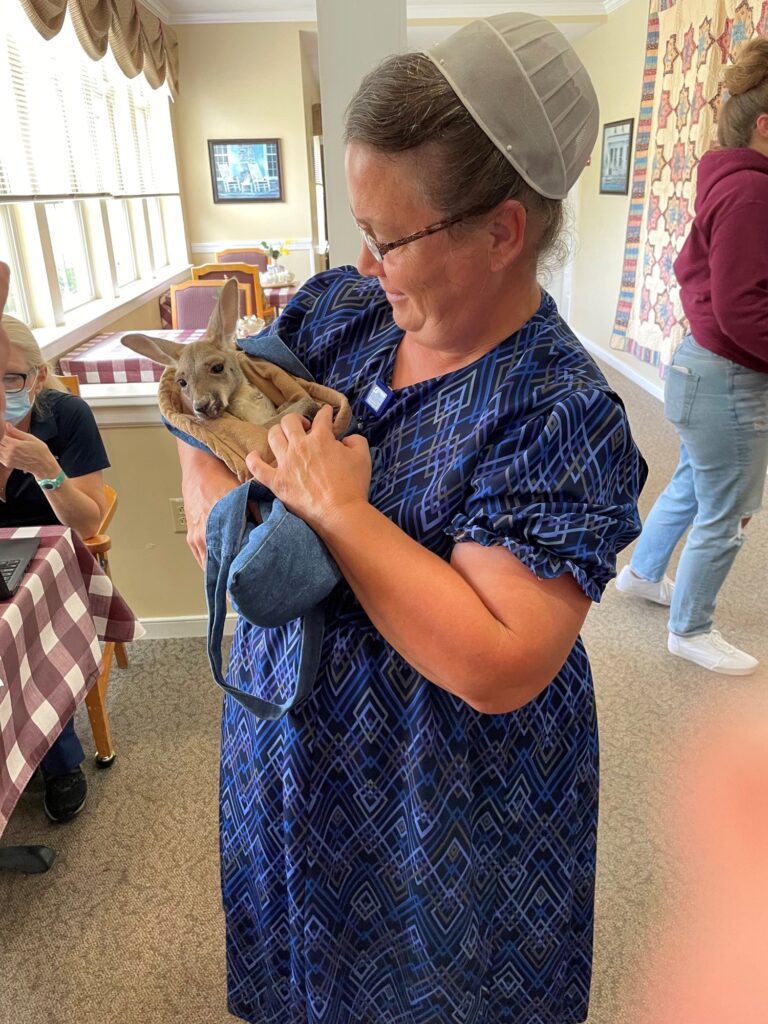 Staff member holding a small animal in a common area.