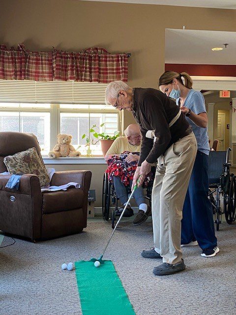 Residents engaged in indoor golf activity.