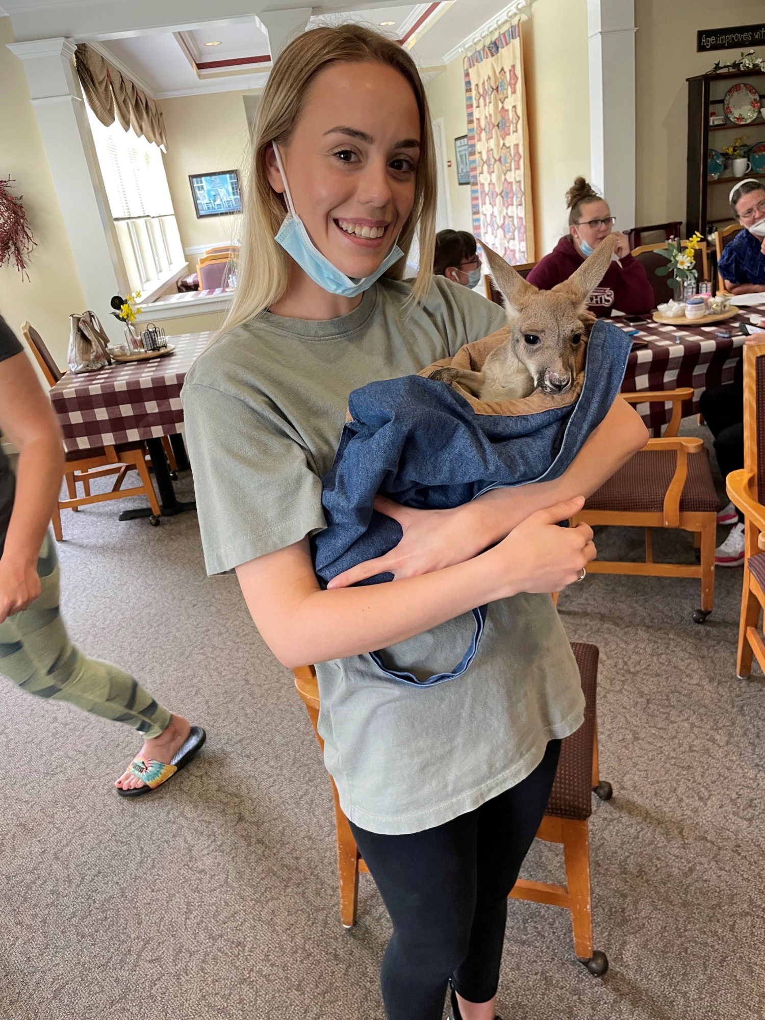 Care staff holding a small animal in a dining area.