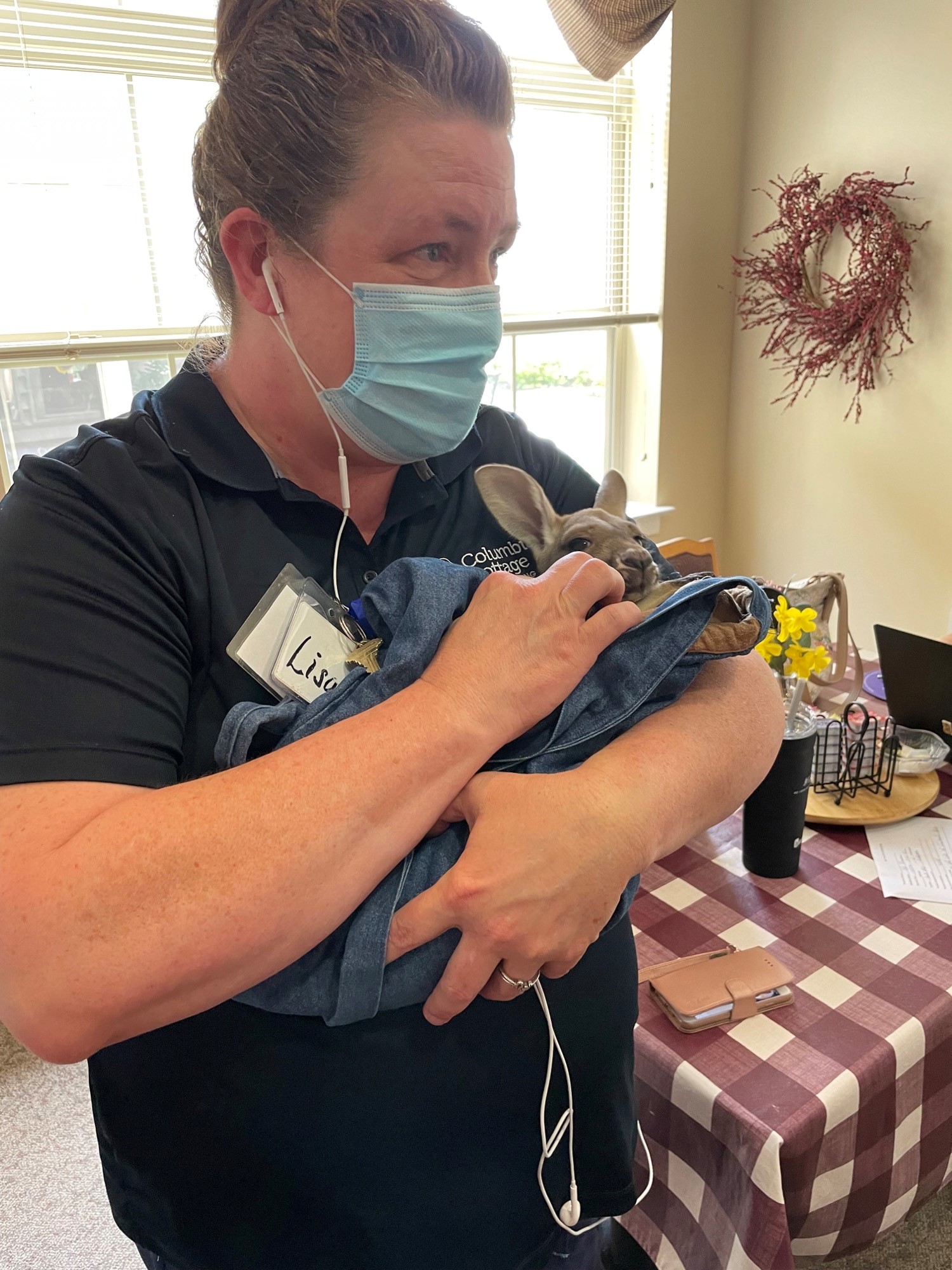 Staff member holding a small dog indoors.