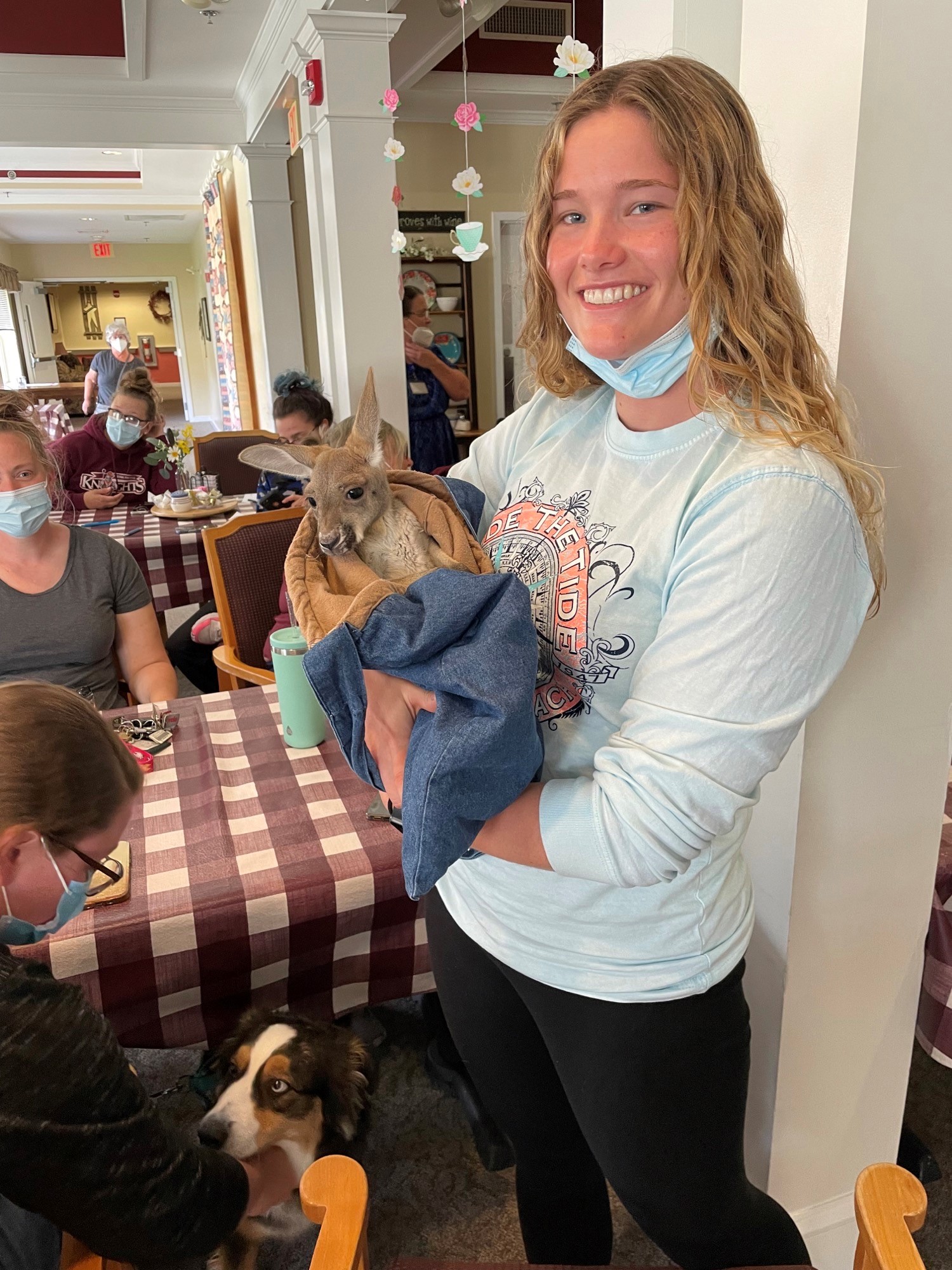 Staff member holding a small animal in a common area.