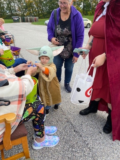 Residents and child enjoying an outdoor Halloween event.