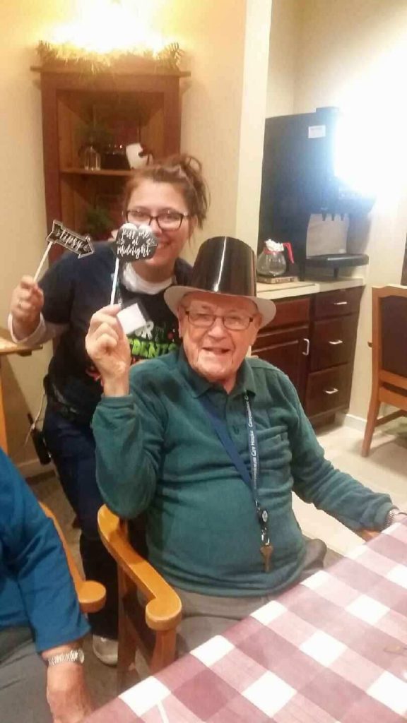 Resident and staff member celebrate together with props.
