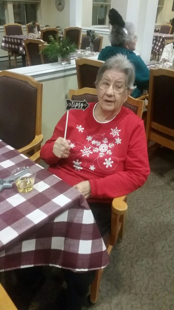 Senior celebrating with a playful sign in dining area.
