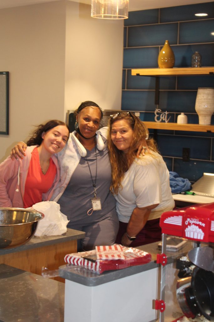 Three staff members smiling in a kitchen area.