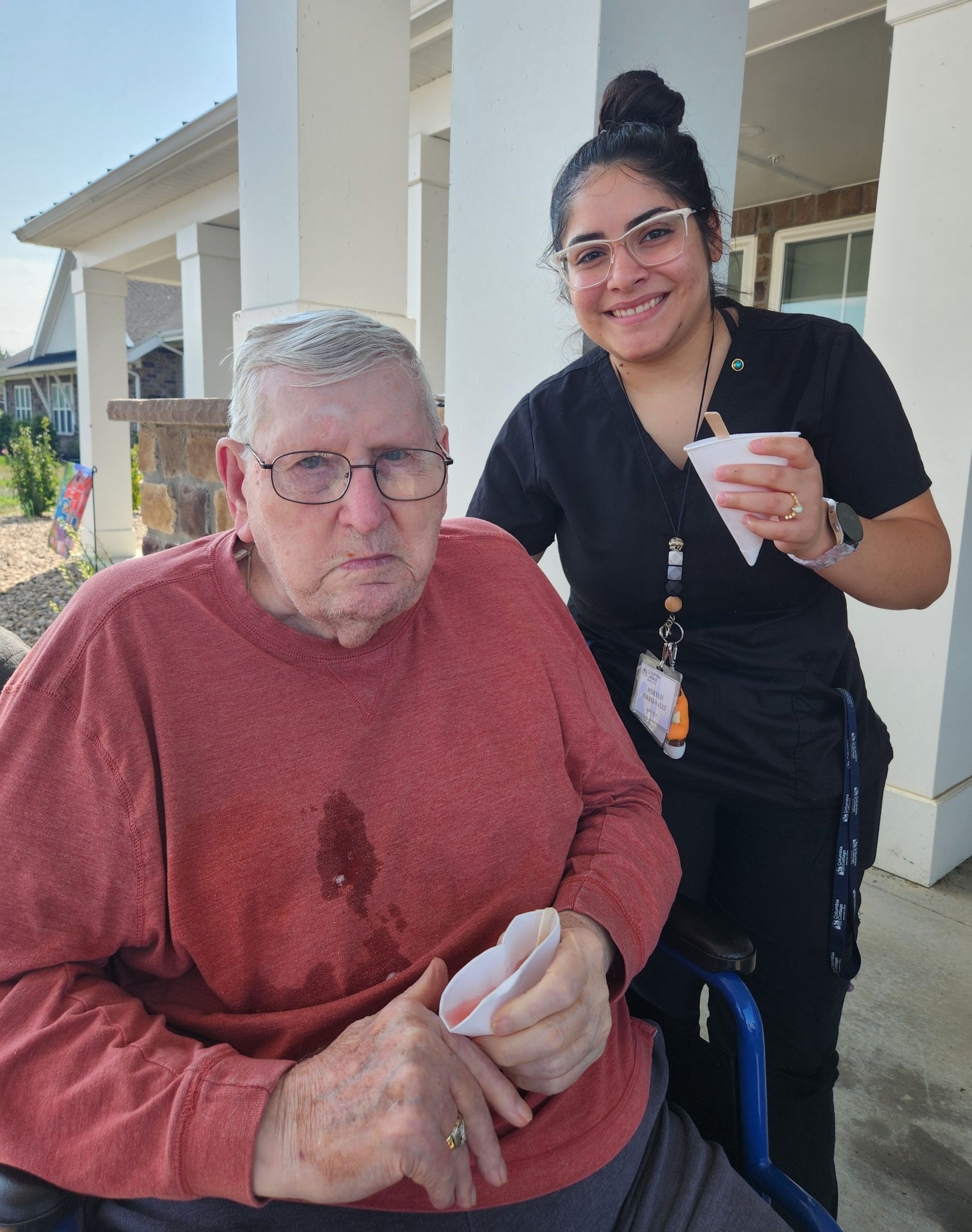 Resident and staff enjoying drinks outdoors.