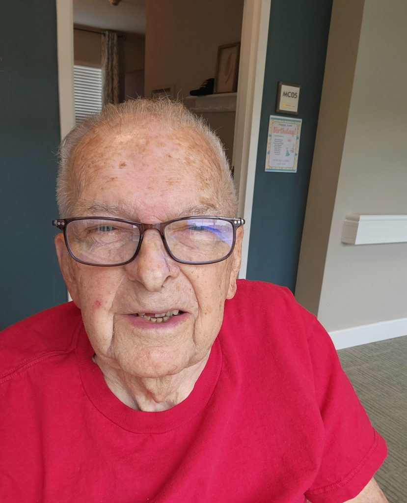 Smiling elderly man in a red shirt indoors