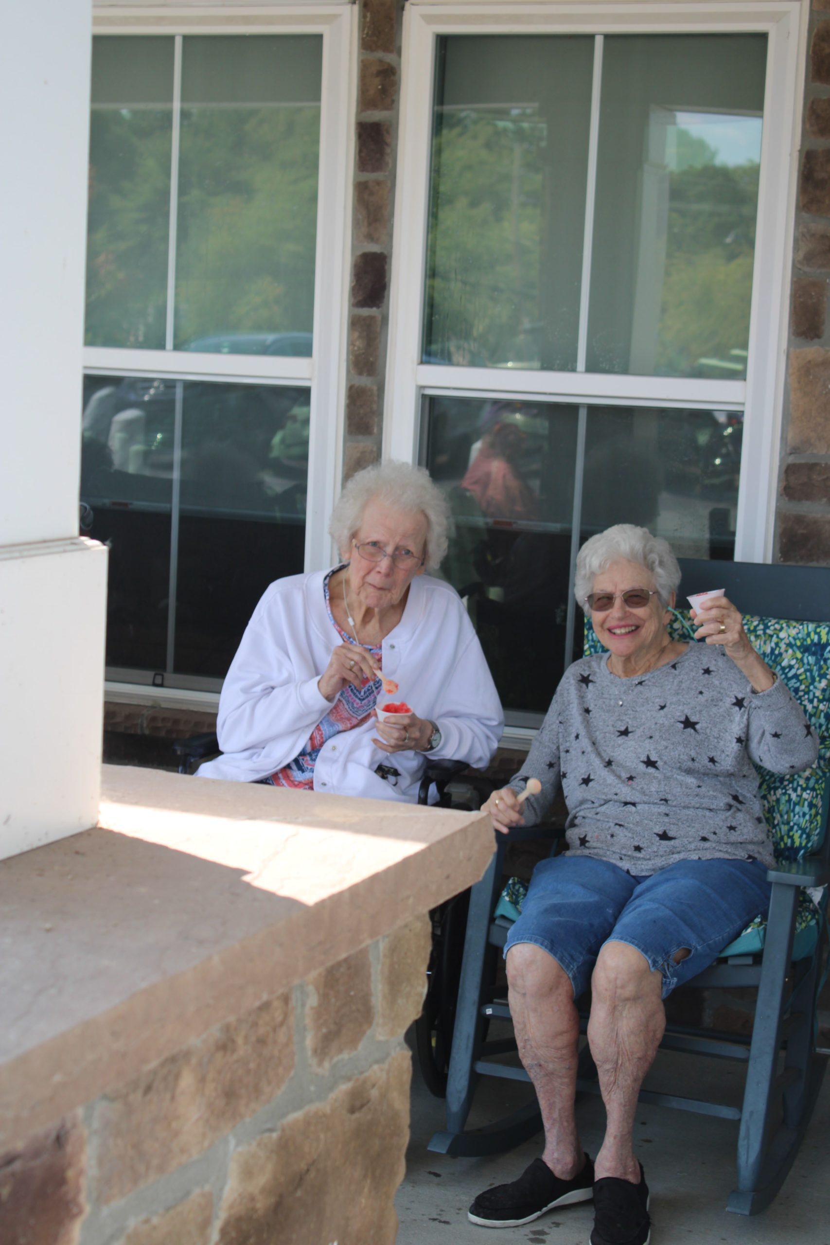 Two elderly women enjoying ice cream outdoors