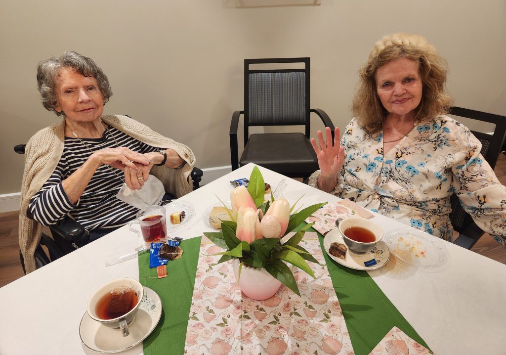 Two residents enjoying tea and dessert together.