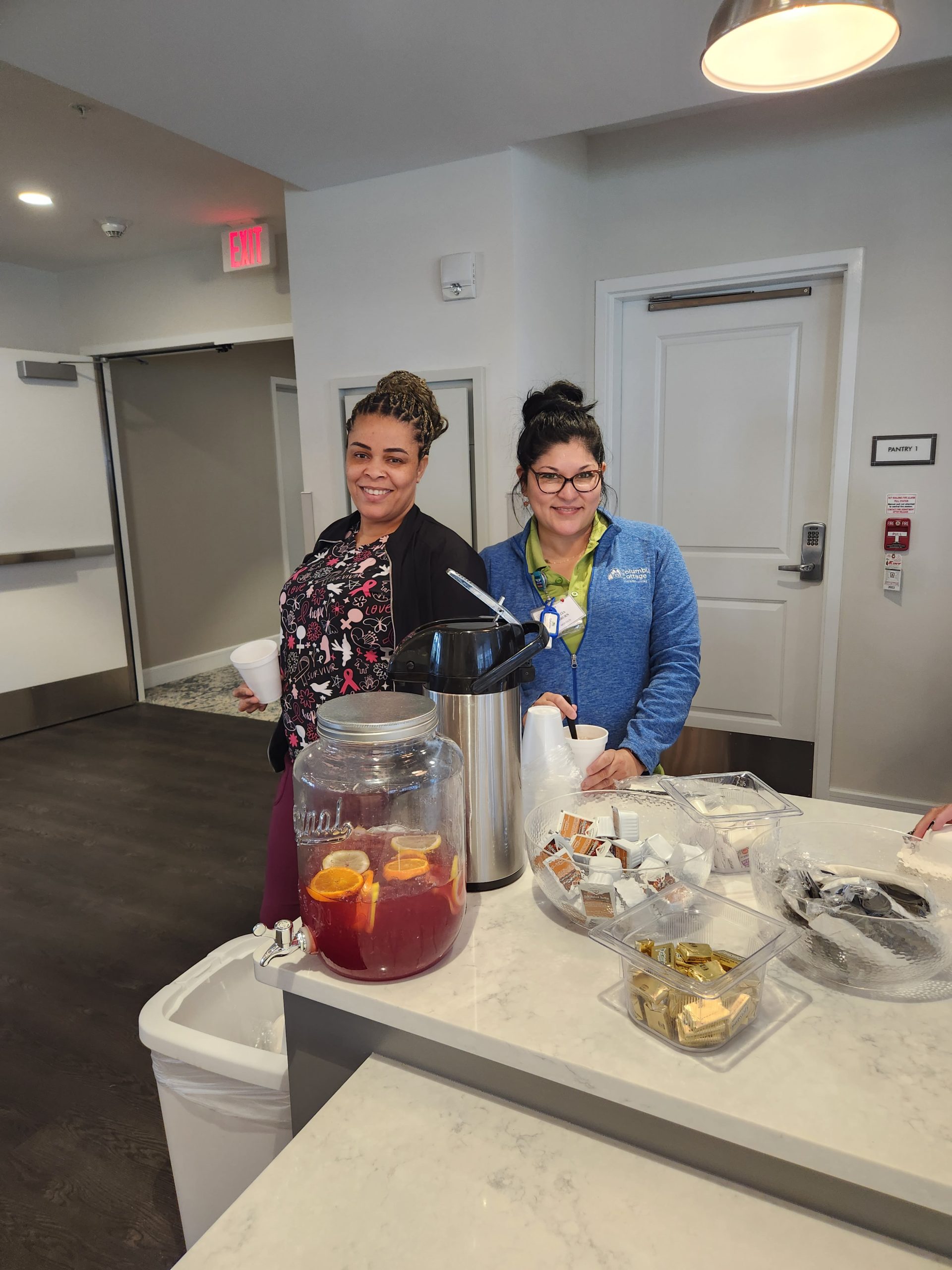 Two staff members serving beverages at a communal area.