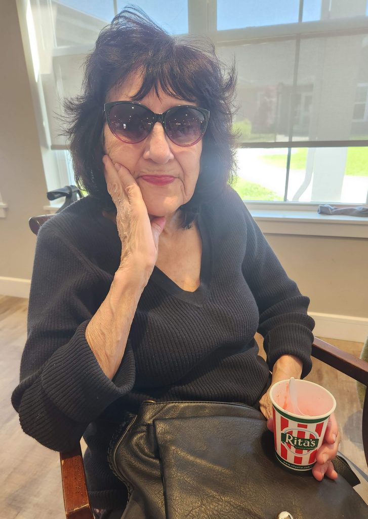 Senior woman in sunglasses enjoying a beverage.
