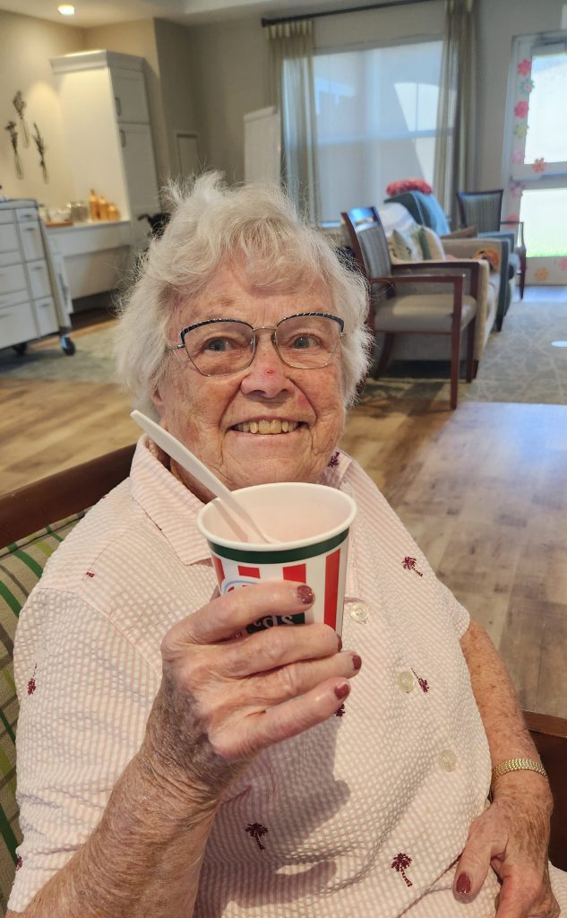 Elderly woman enjoying a treat in a common area.
