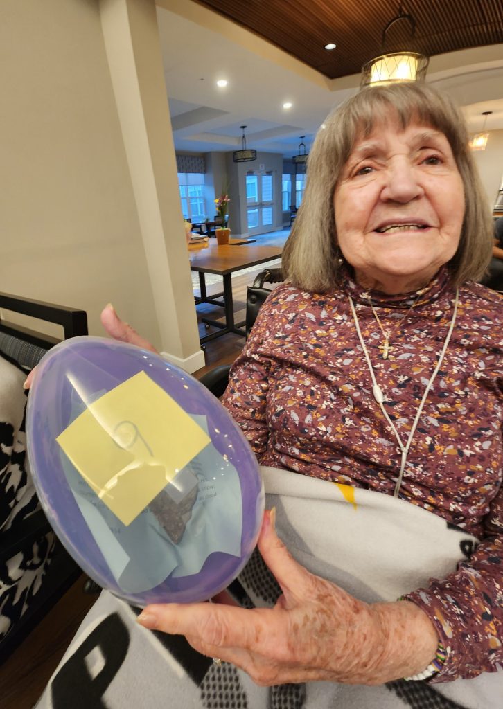 Elderly woman holding a colorful plastic egg.
