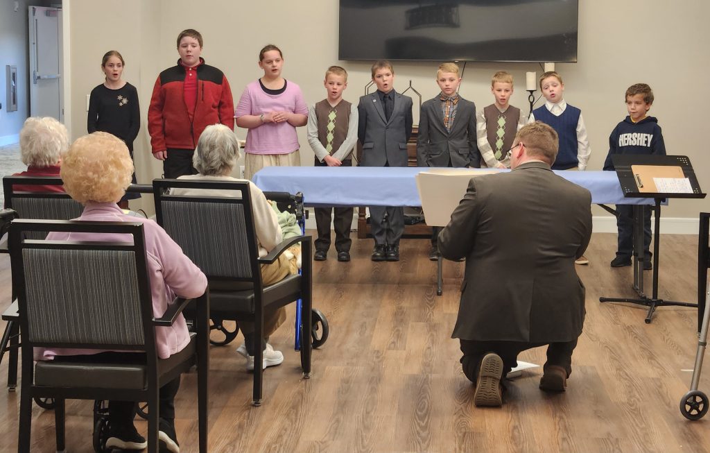 Children performing for seated residents during an event.