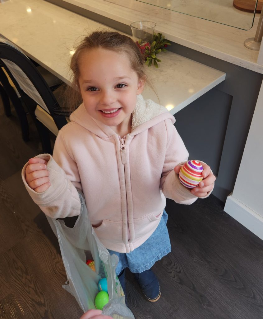 Child holding decorated eggs in a facility interior