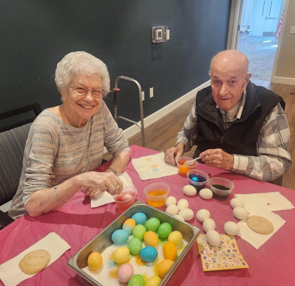 Two residents decorating eggs at a table