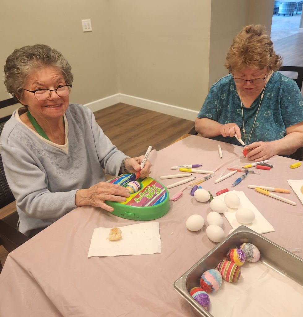 Two senior women painting decorative eggs