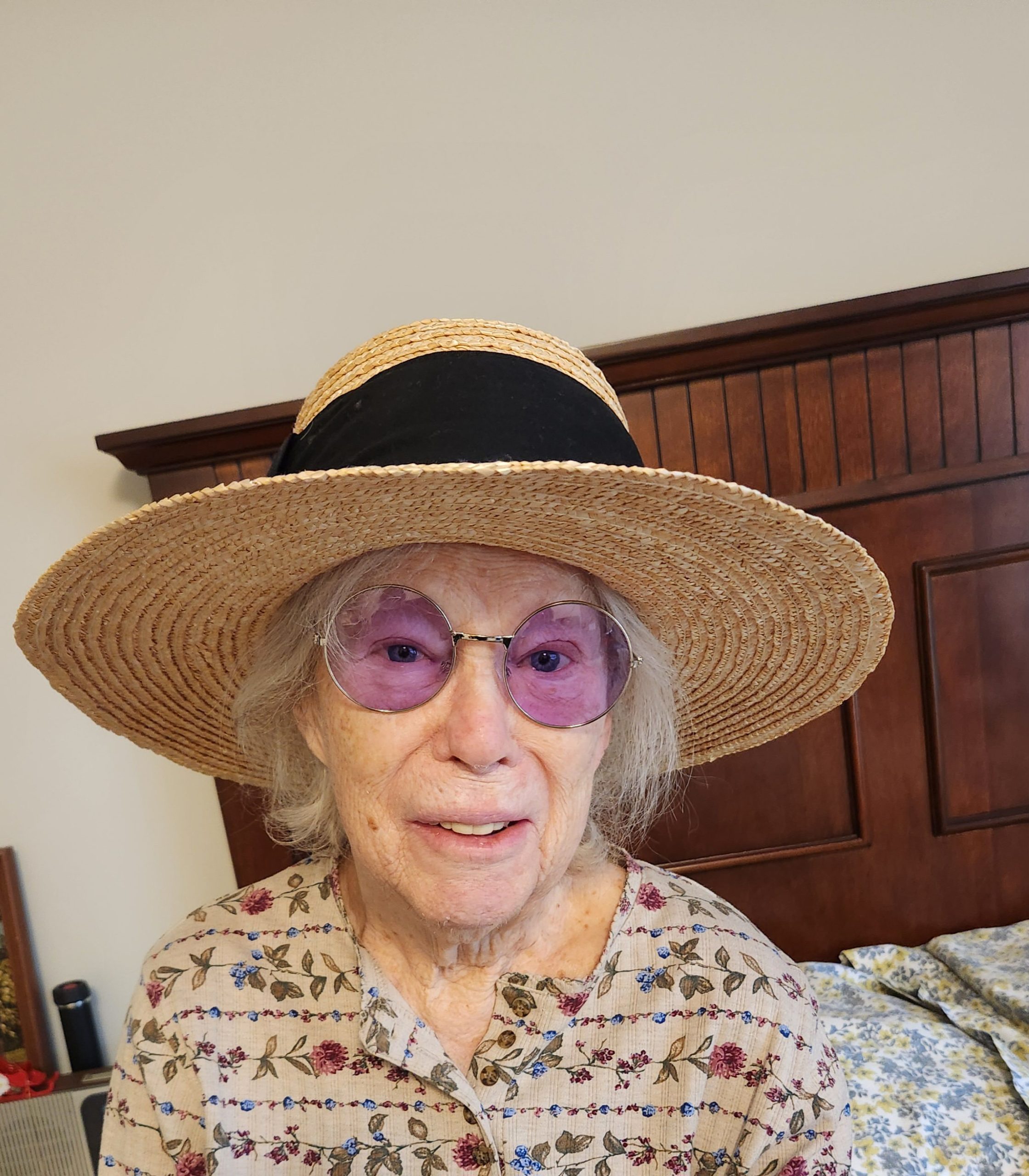 Elderly woman wearing a sun hat and sunglasses.