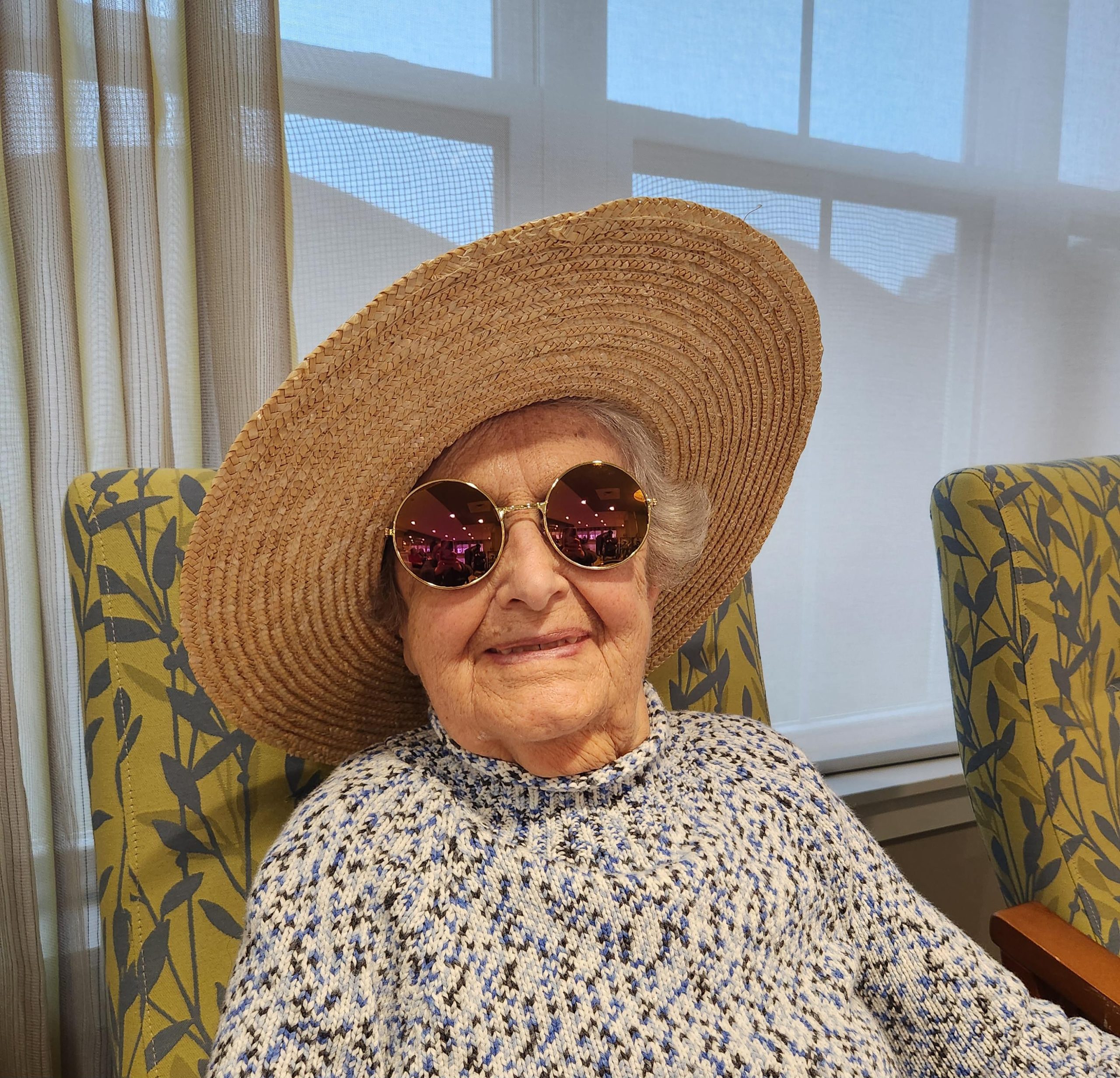 Elderly woman wearing sunglasses and a large hat