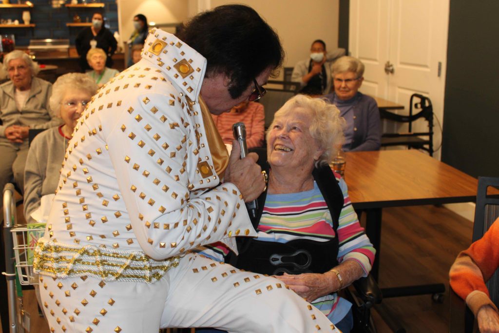 Elvis performer engaging with resident during an event.