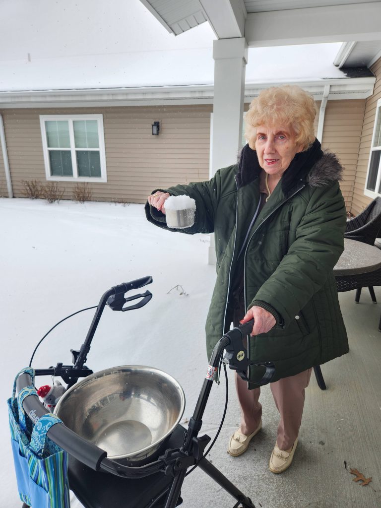 Senior woman enjoying snow outside with walker.