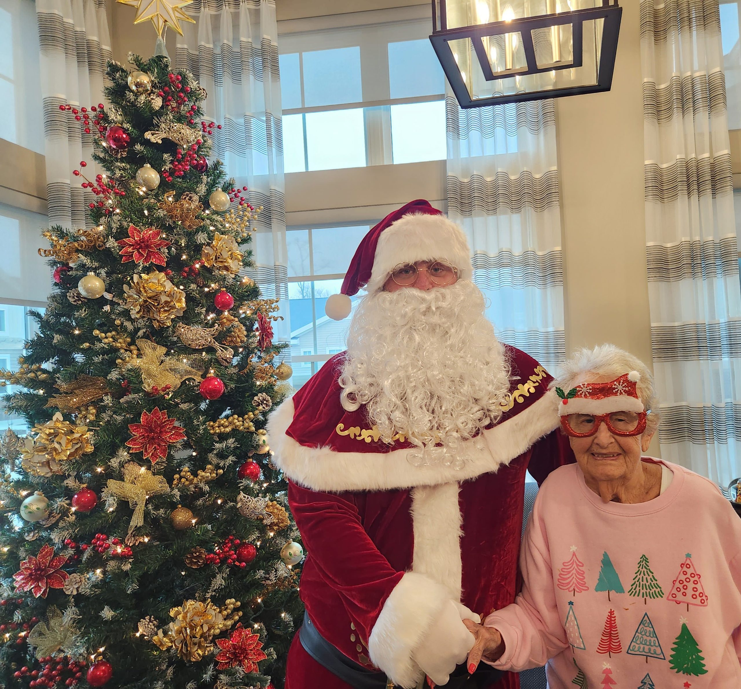 Resident with Santa Claus by a decorated Christmas tree