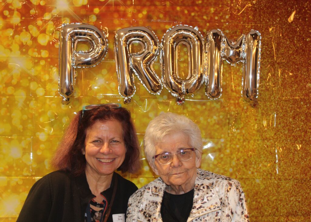 A smiling woman with an elderly resident at a prom event.