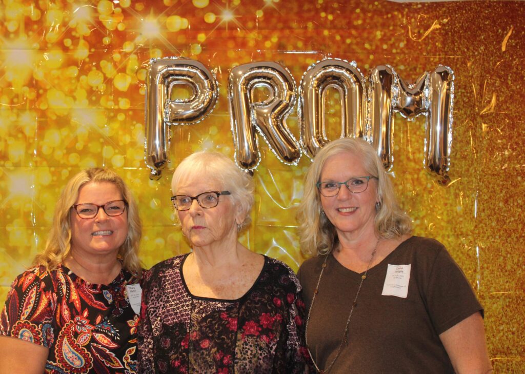 Three women posing at a prom-themed event