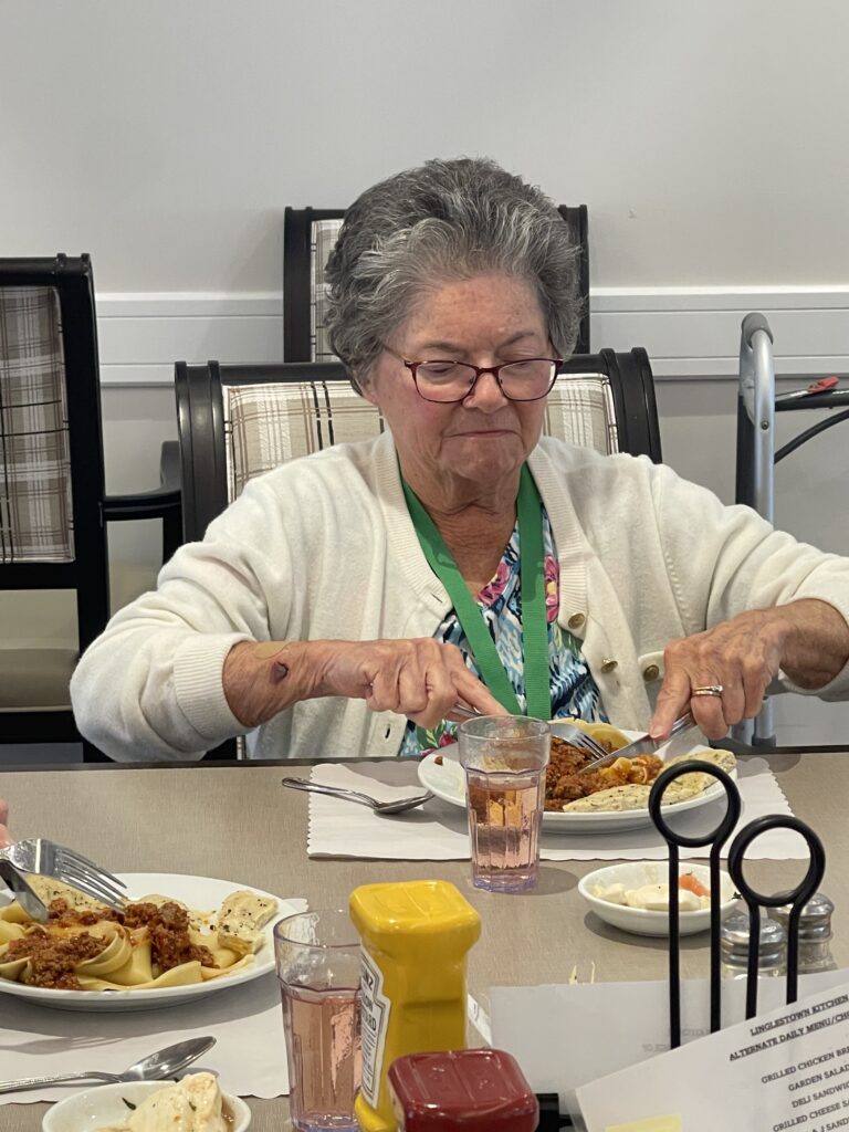 Elderly woman enjoying a meal in the dining room.