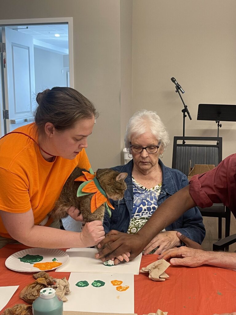Residents and staff engage in art activity with a cat.