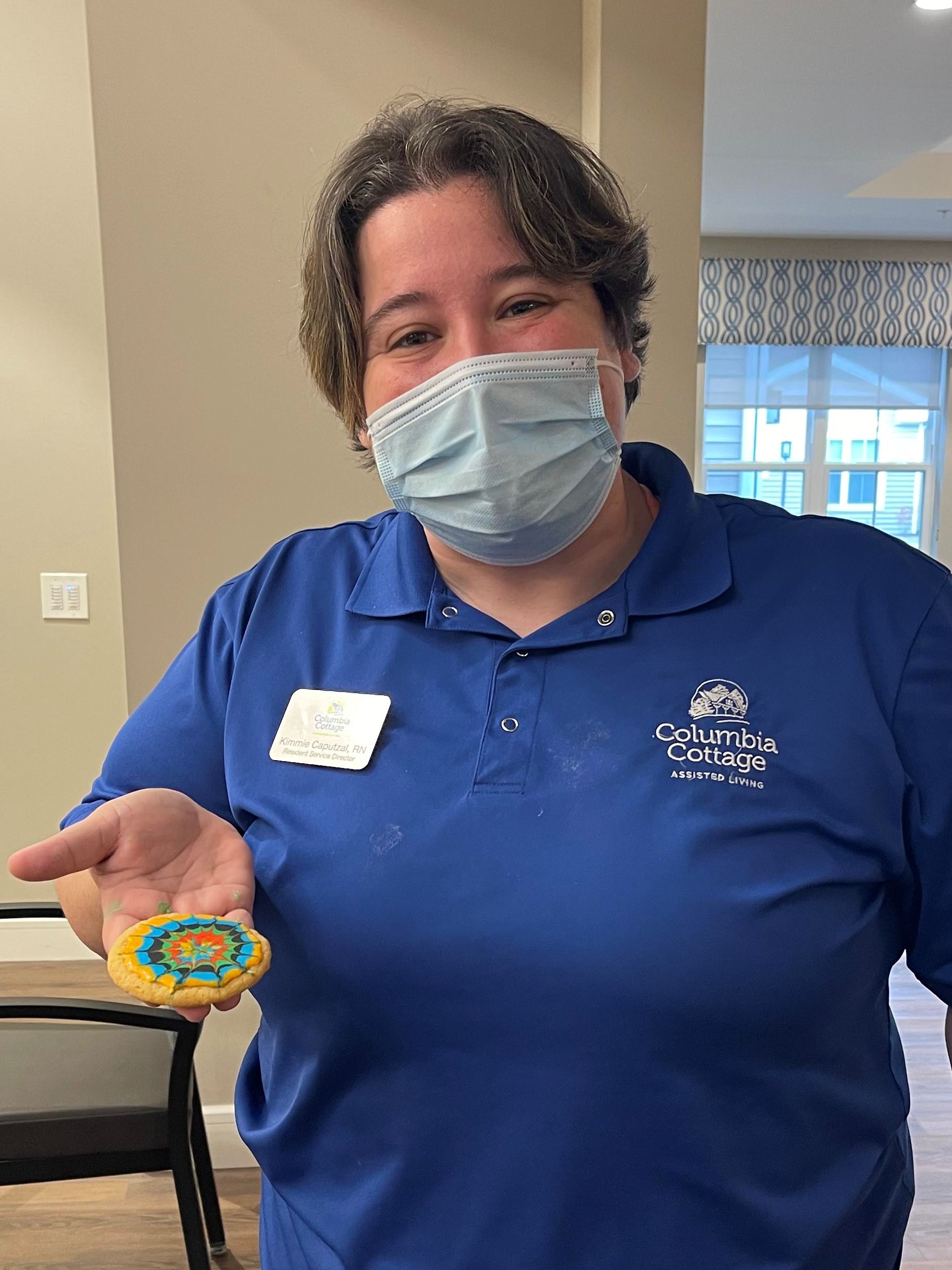 Staff member holding a decorated cookie.