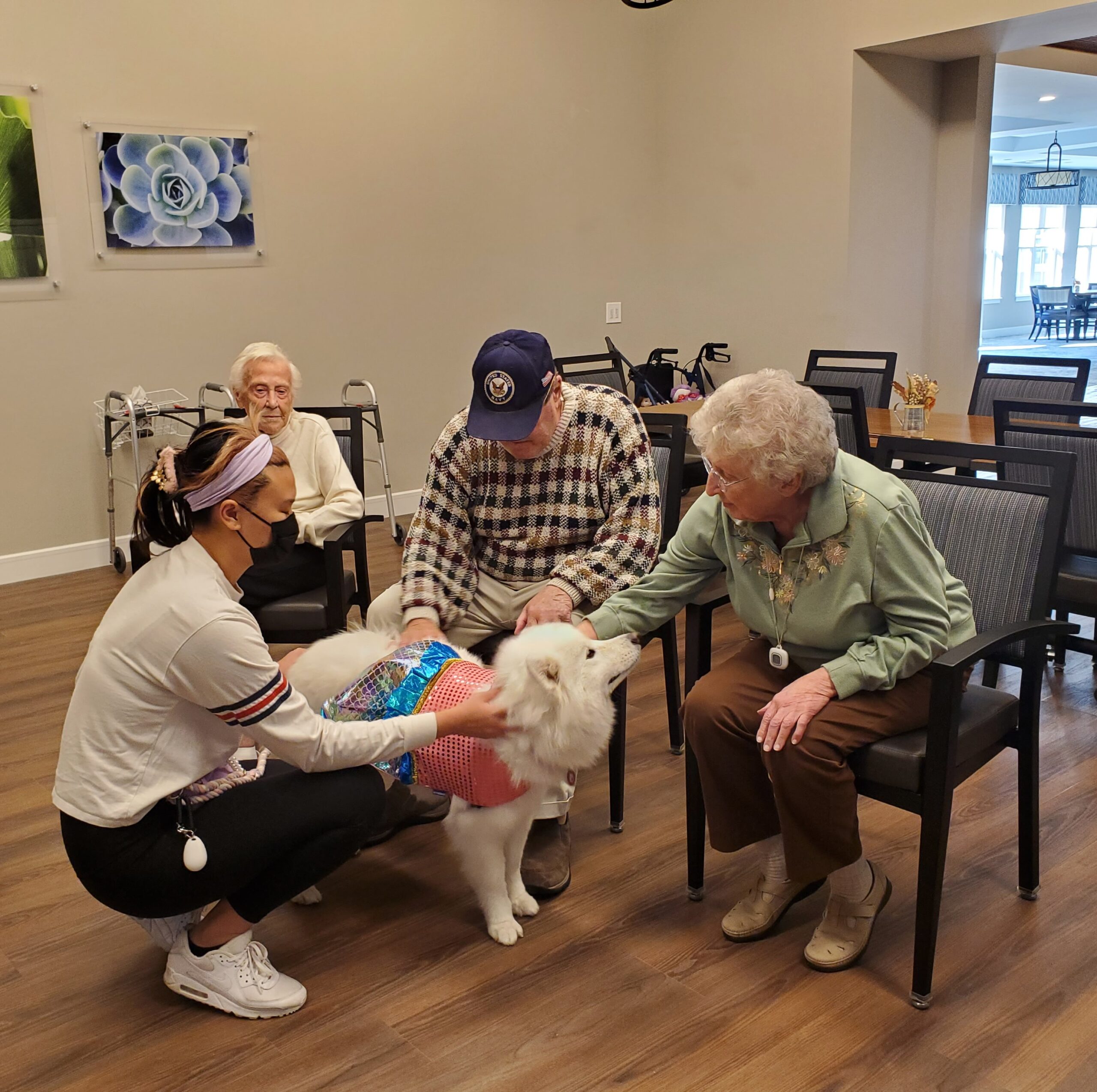 Residents interacting with a therapy dog in a social area.