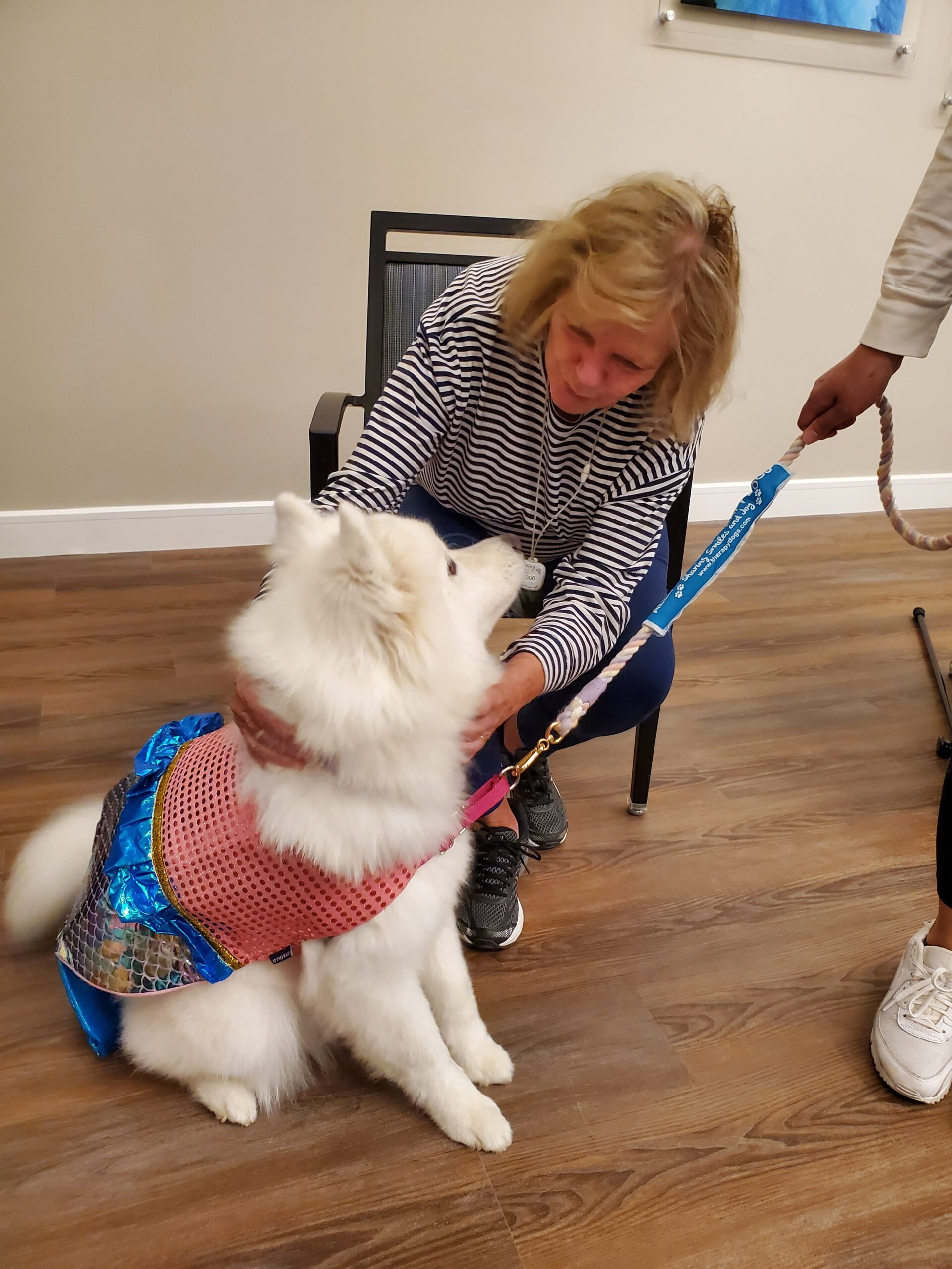 Resident interacting with a therapy dog indoors.