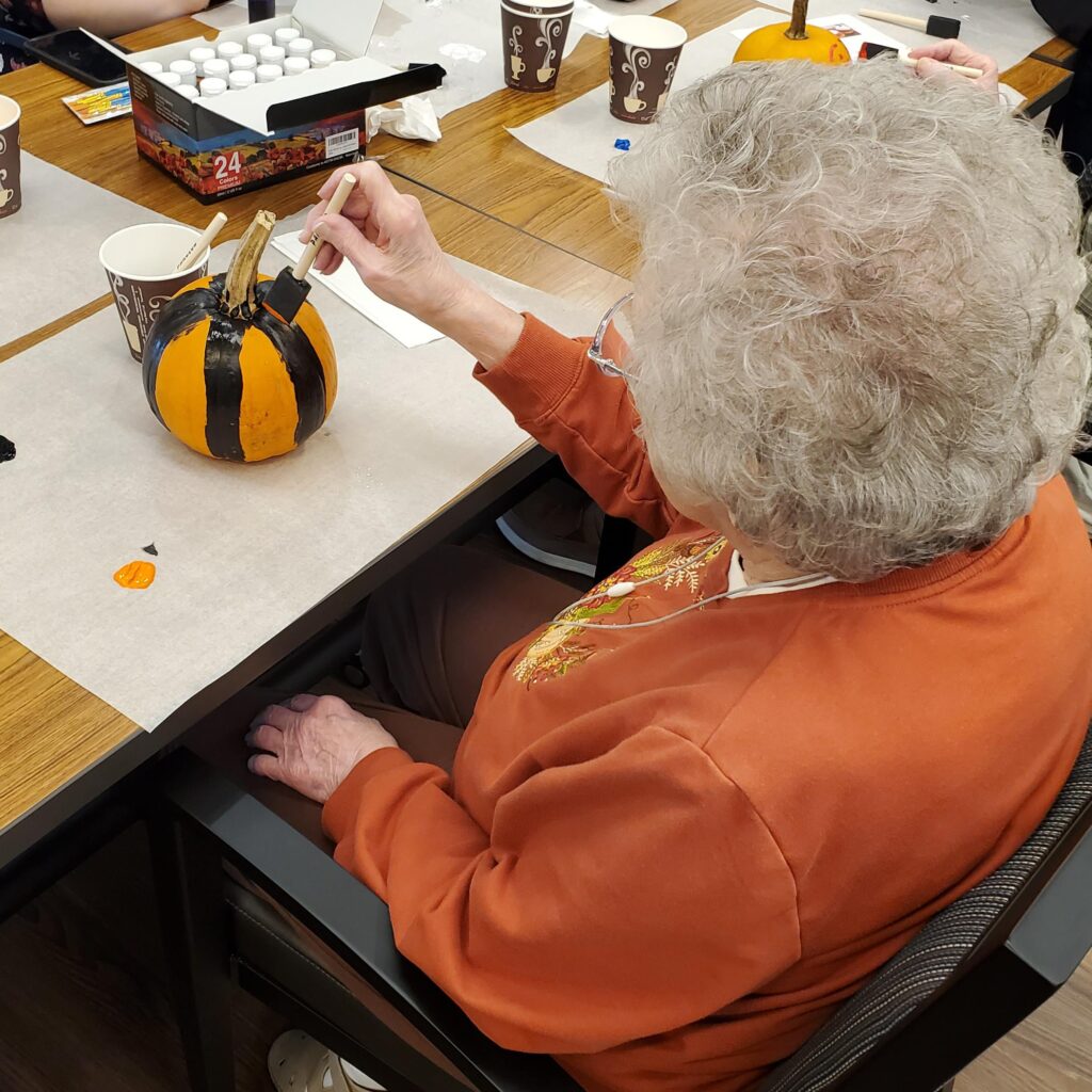 Resident painting a pumpkin during an activity.