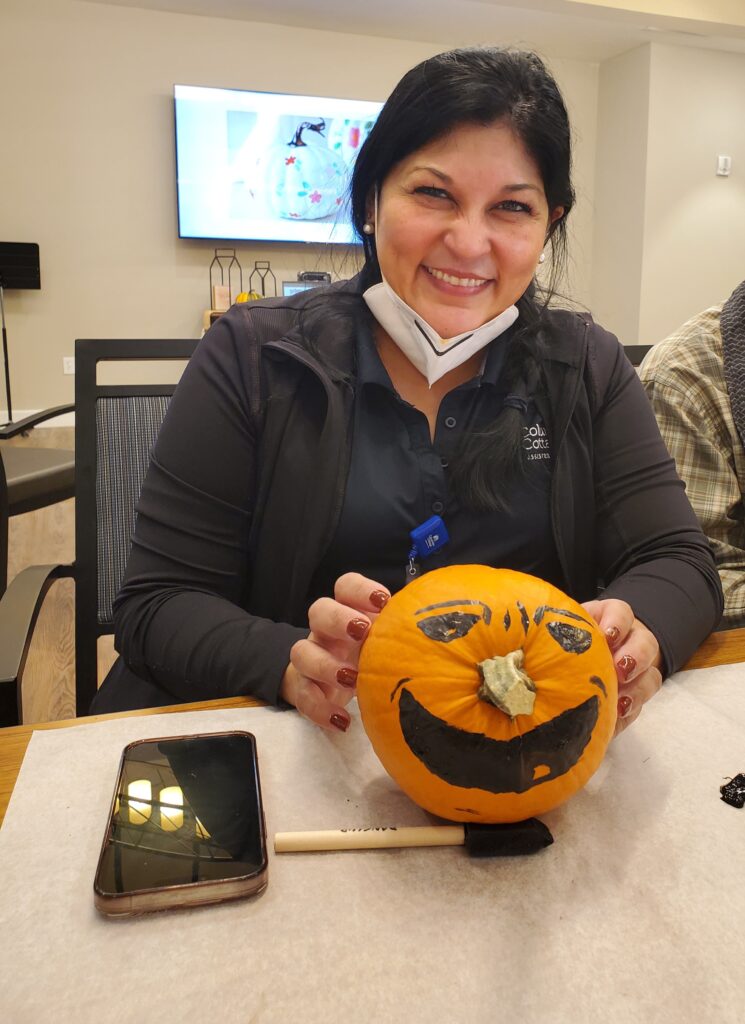 A staff member showing a painted pumpkin.