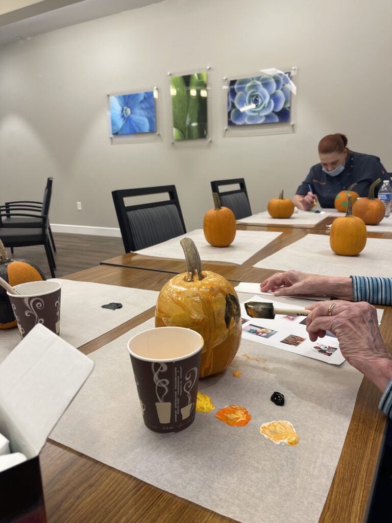 Residents painting pumpkins in a common area