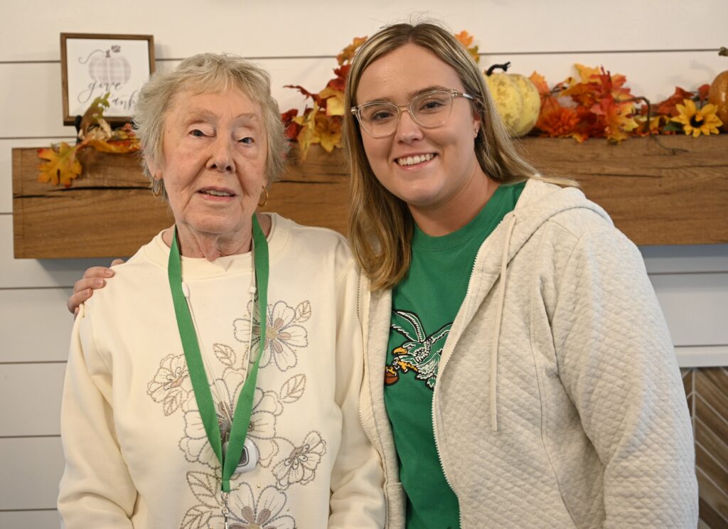 Resident and staff member posing together indoors.