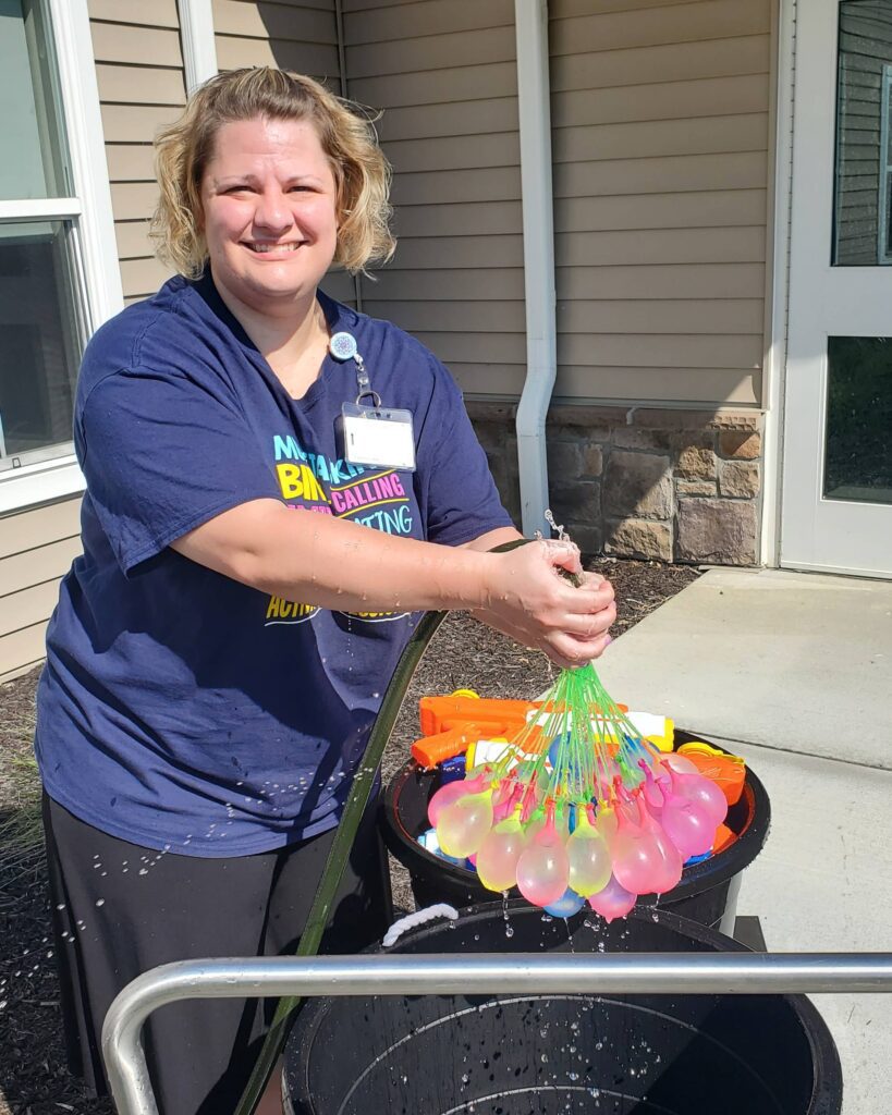 Staff member engaging residents with water balloons.
