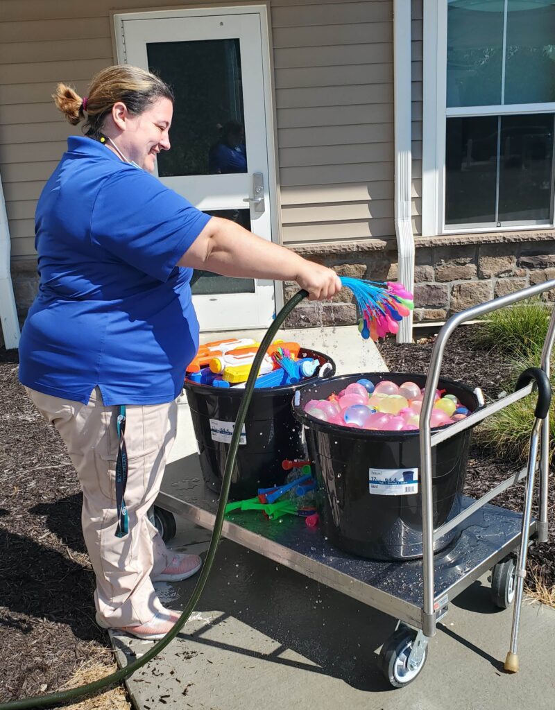 Staff member washing colorful activity toys outside.