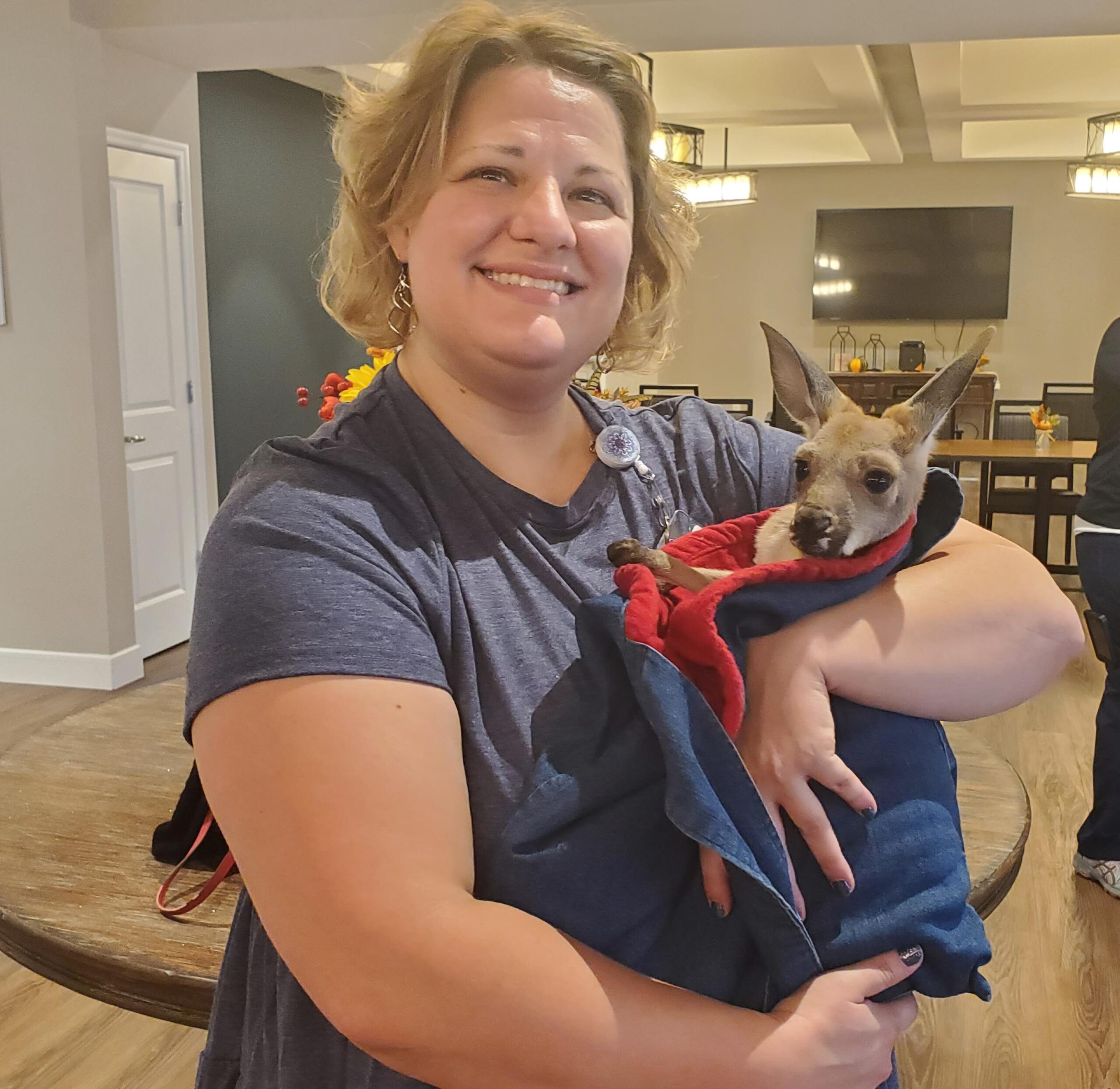 Staff member holding a pet kangaroo indoors.