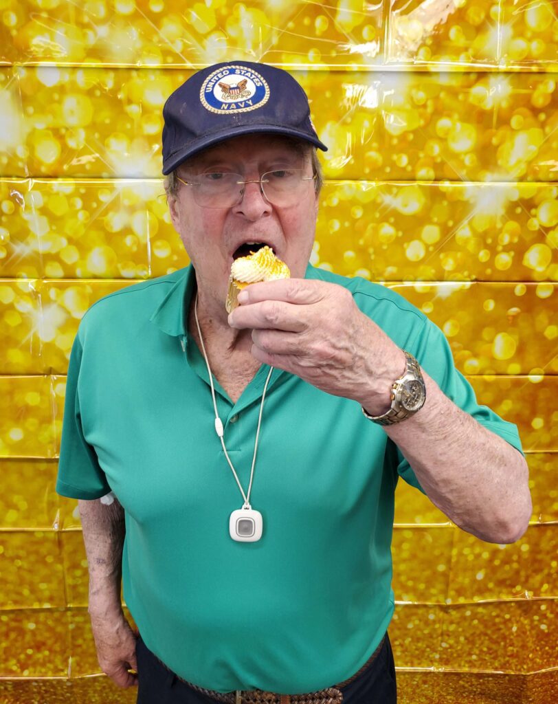 Elderly man enjoying a dessert treat indoors.