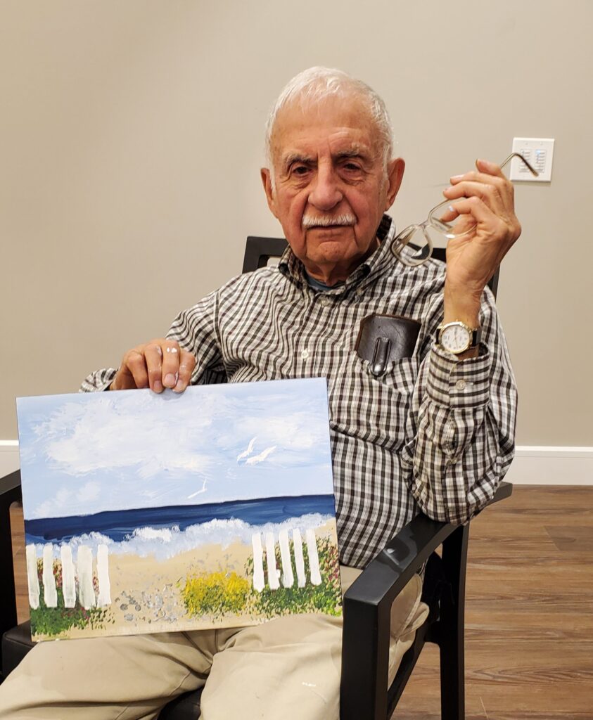 Elderly resident holding a painting at the facility