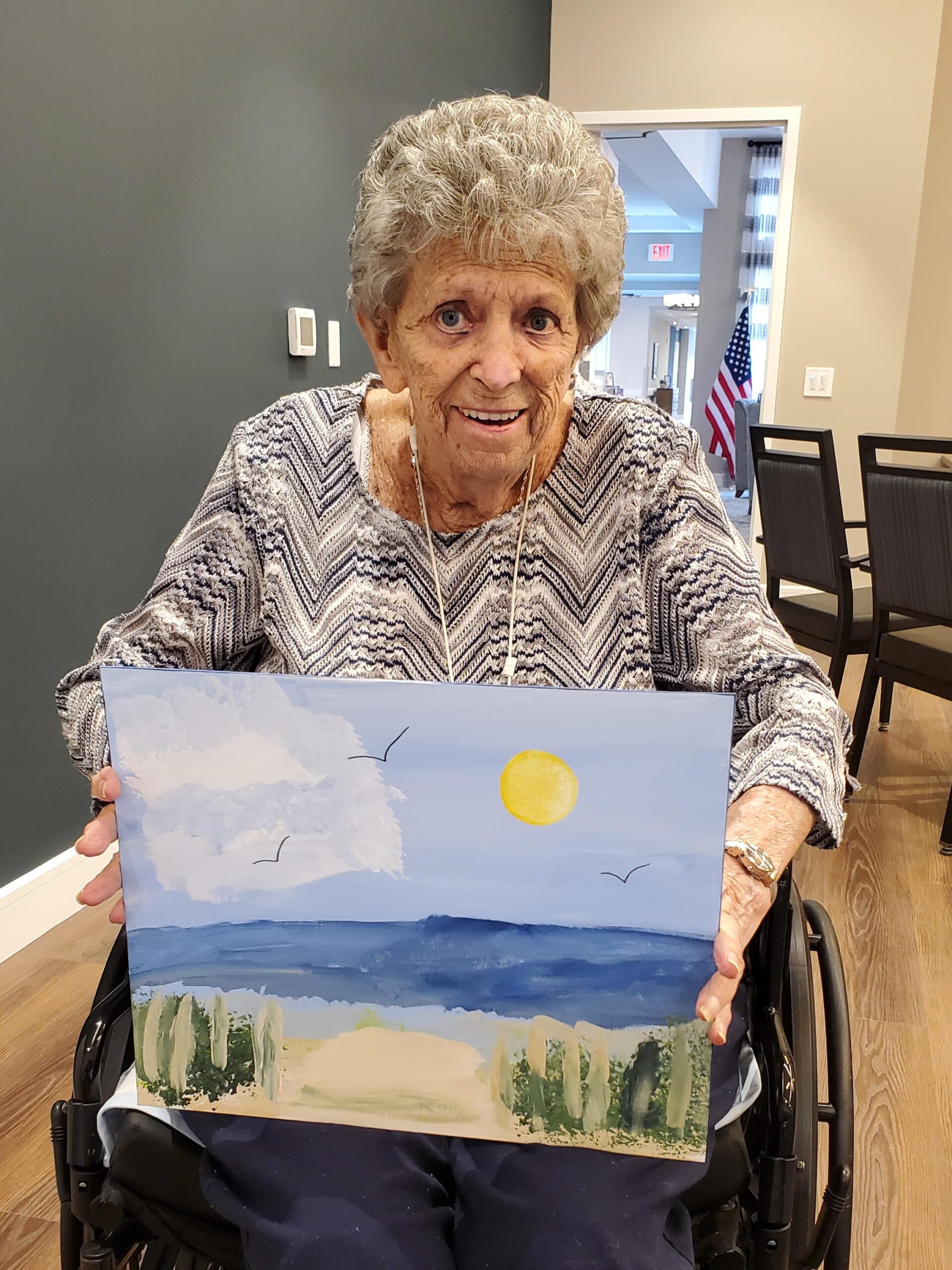 Elderly woman displaying her painting in a common area.