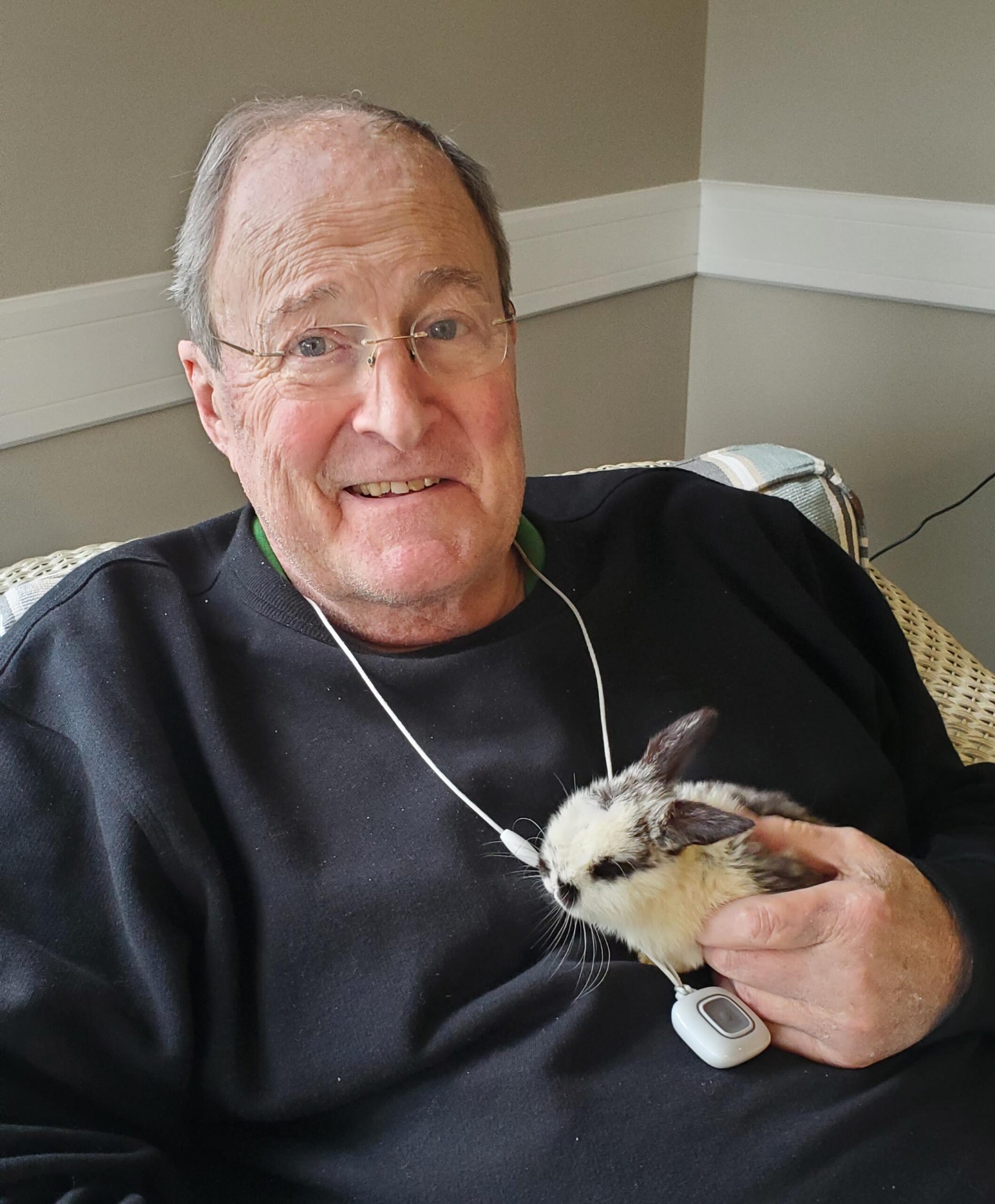 Senior man holding a rabbit in a cozy setting.