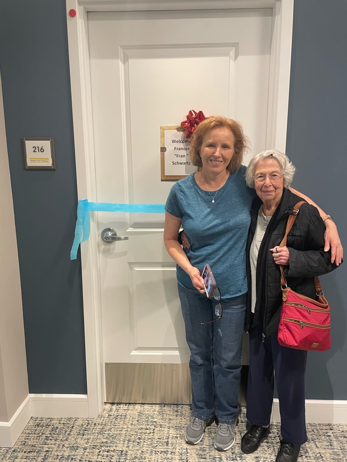 Two women posing in front of a resident door.